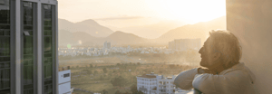 Woman with short hair leaning on a balcony overlooking a city view